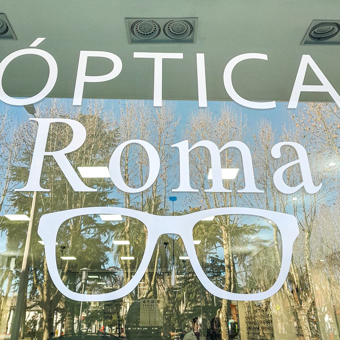 Vidriera de Óptica Roma con los árboles de la plaza de Las Piedras reflejados